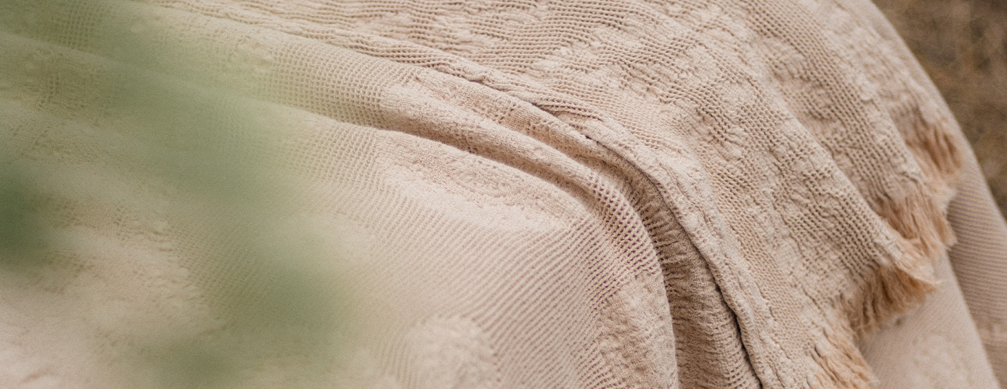 Manta texturizada en tonos naturales y beige, que refleja el confort y la sofisticación de los productos Cama em Ponto.